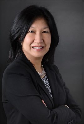 A picture of Joannie Chin, who wears a dark jacket and smiles toward the camera