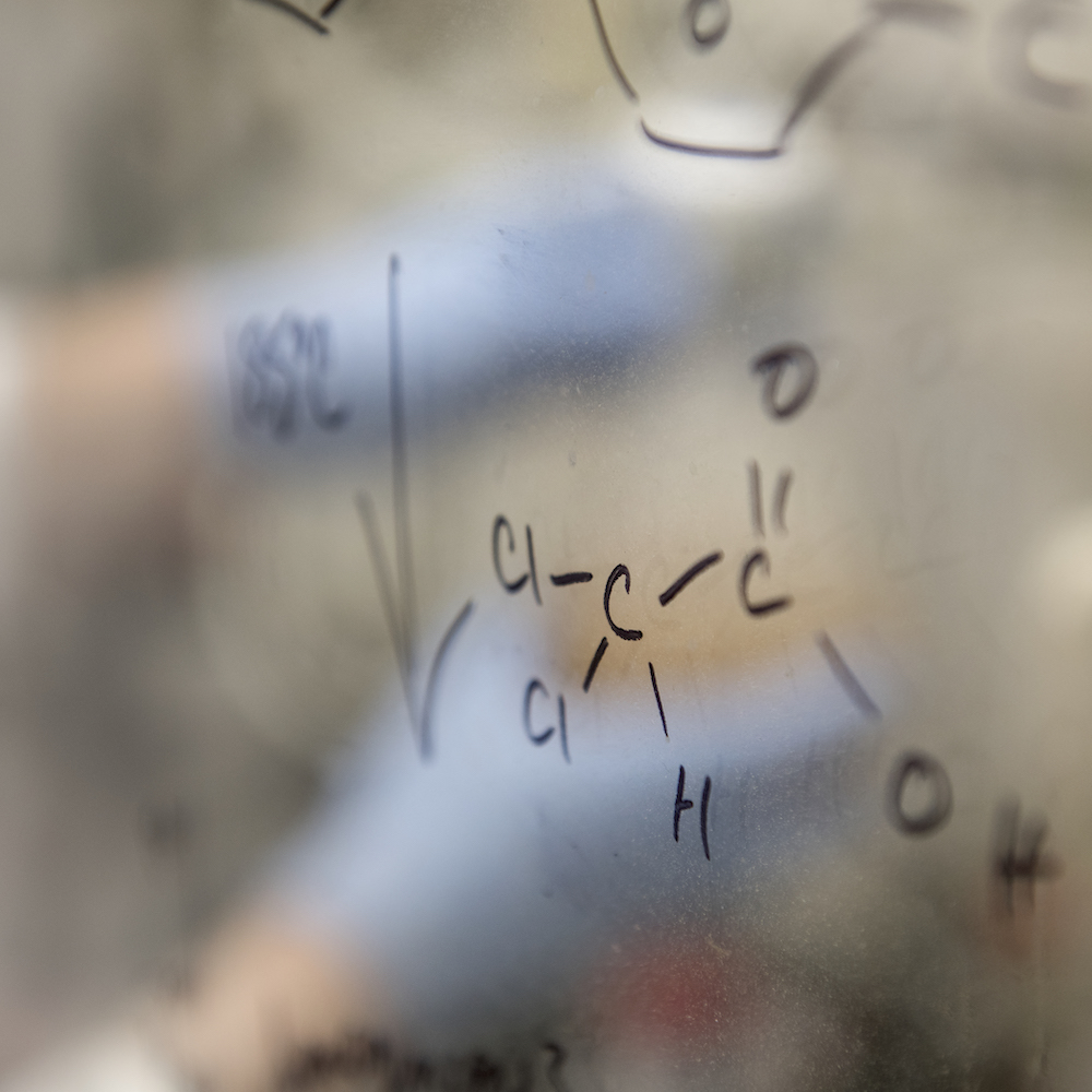 Polymer-related work is drawn on a white board in a lab.