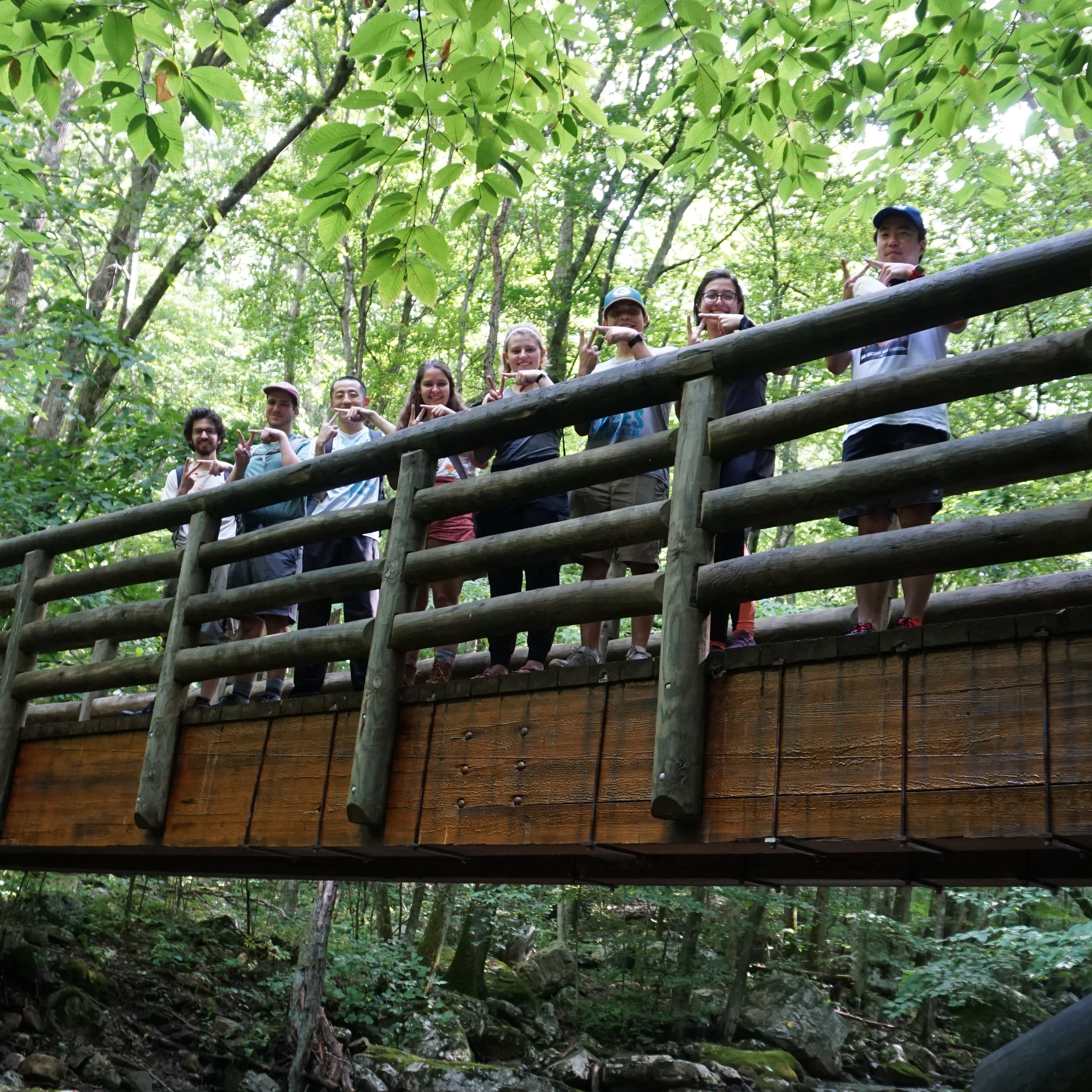 Six new macro students and two current macro students stand in front of the venture out ropes course at Virginia Tech.