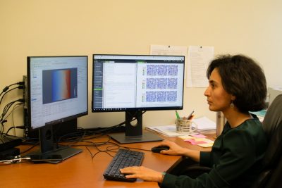 Maryam Shakiba sits at her desk while working on computational modeling on two computer monitors.