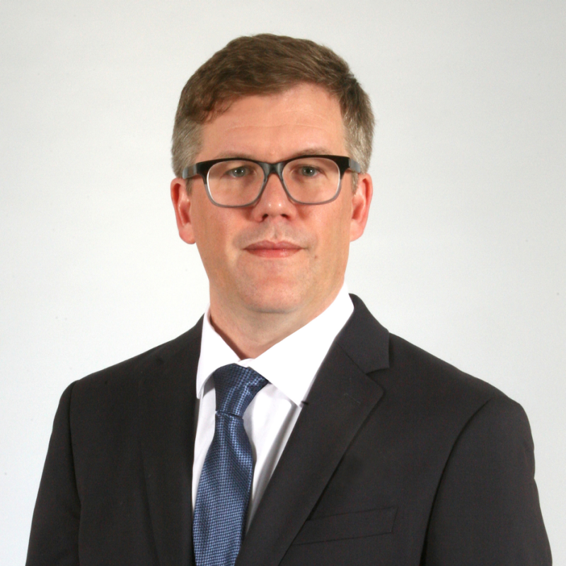 A picture of Jonathan Goff, who wears a suit and glasses