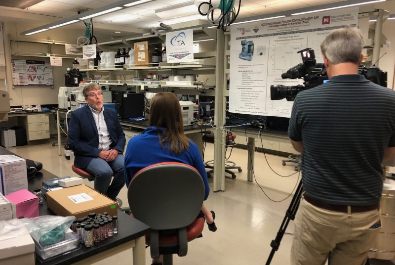 Tim Long is interviewed by an anchor from W-S-L-S and a cameraman in the M-M-D-C lab at Virginia Tech. Long wears a navy blazer and white button down shirt.